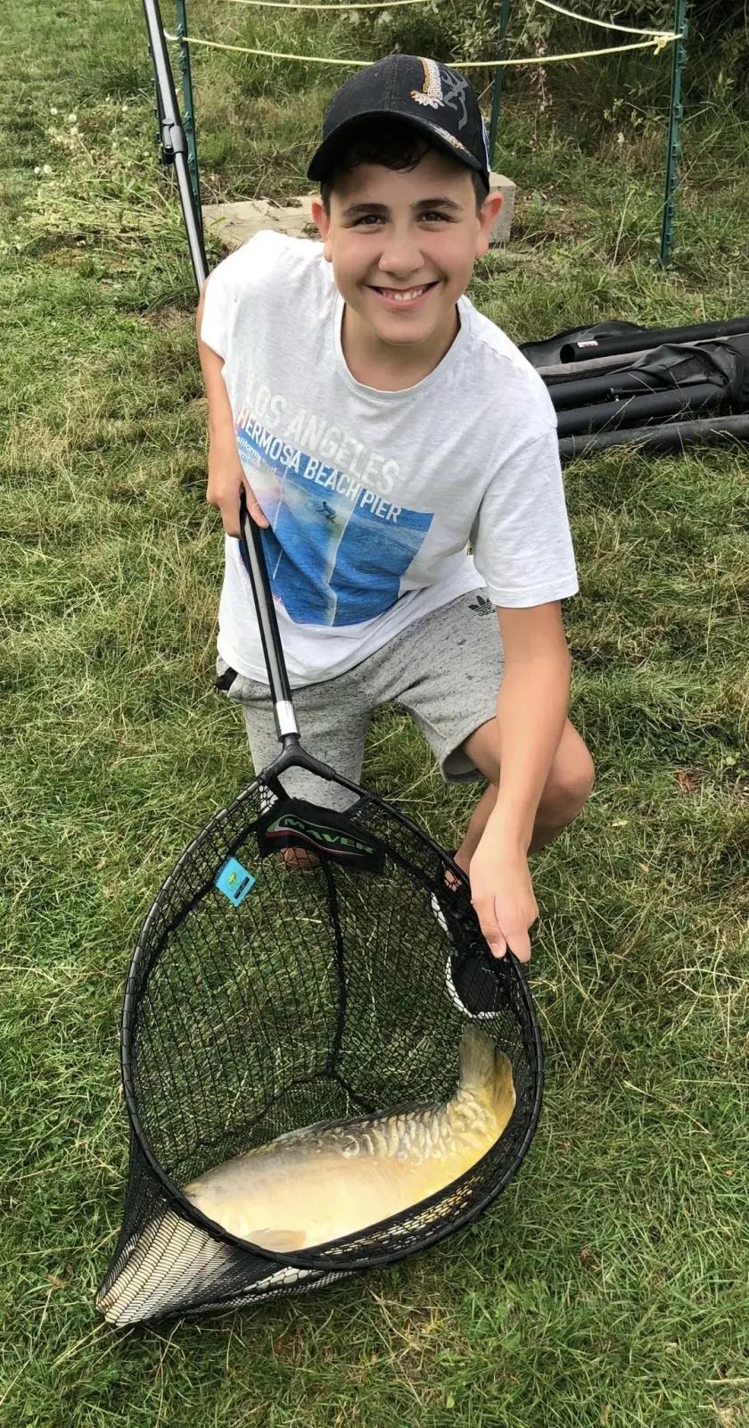 Jamie holding a fishing net with a large carp he caught.