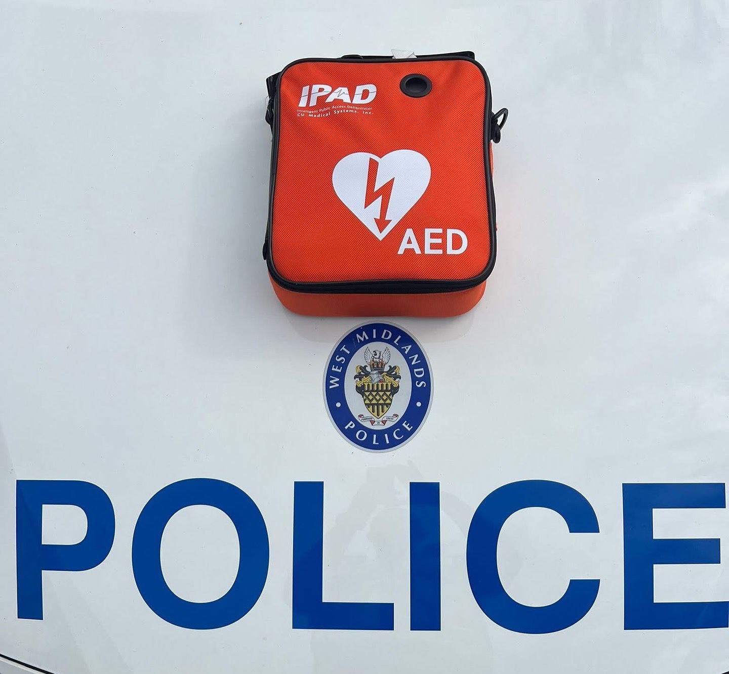 Close-up of the orange iPAD AED defibrillator bag resting on a West Midlands Police vehicle.