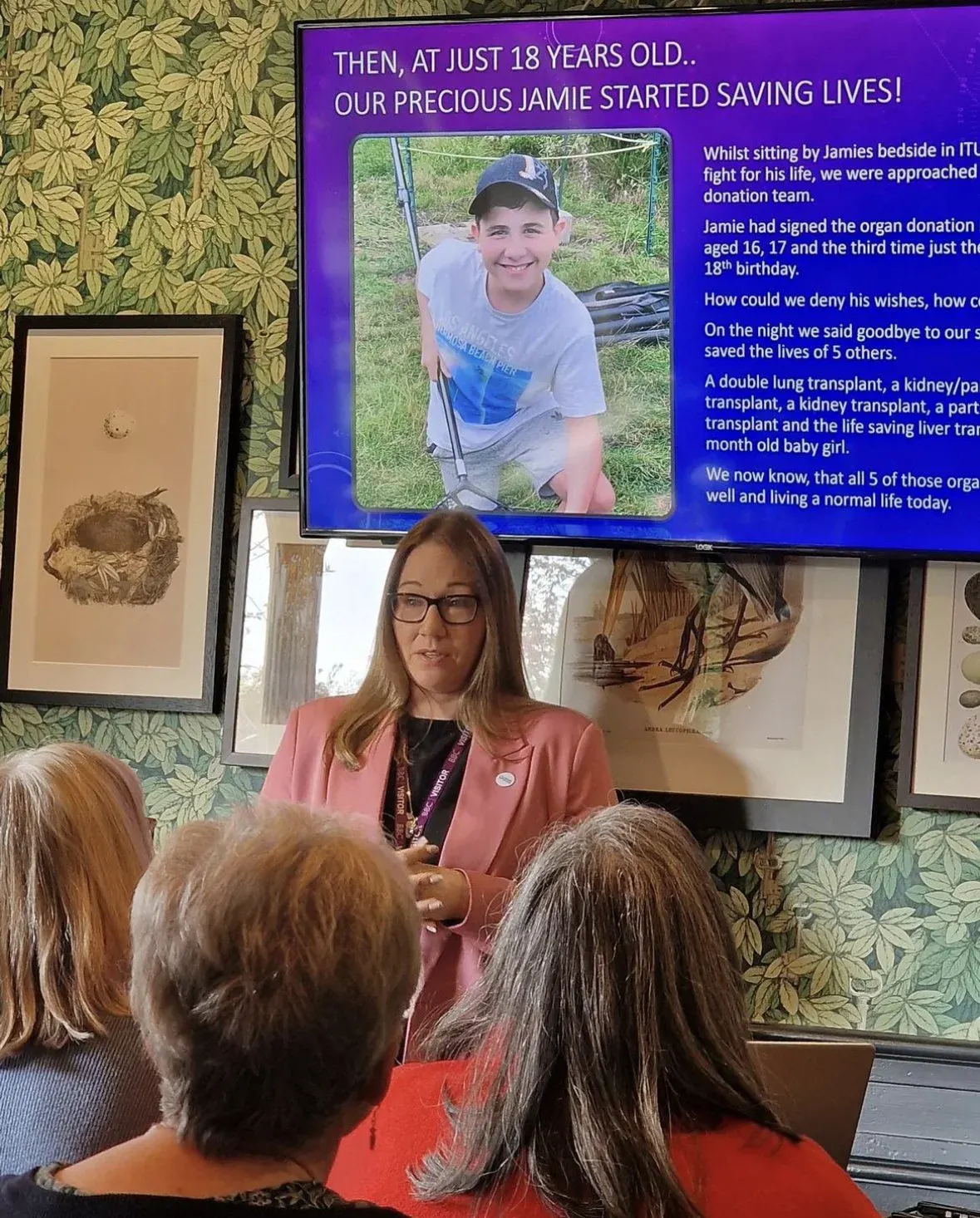 Naomi Rees-Issitt giving a talk in front of a screen showing Jamie's photo and the headline about his organ donation.